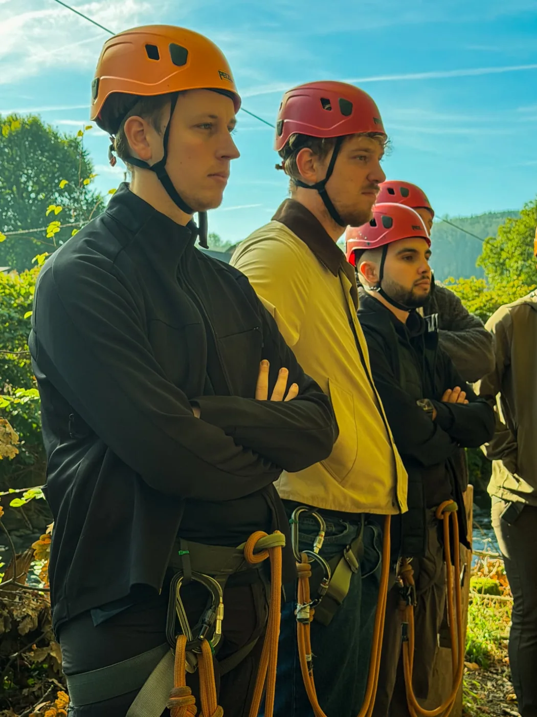 Teammates wearing helmets and harnesses during an outdoor adventure briefing