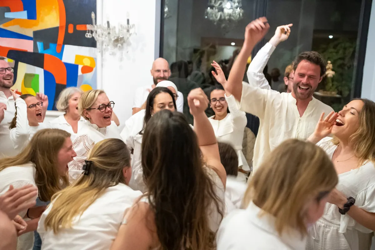 Guests in white dancing and laughing at an evening celebration